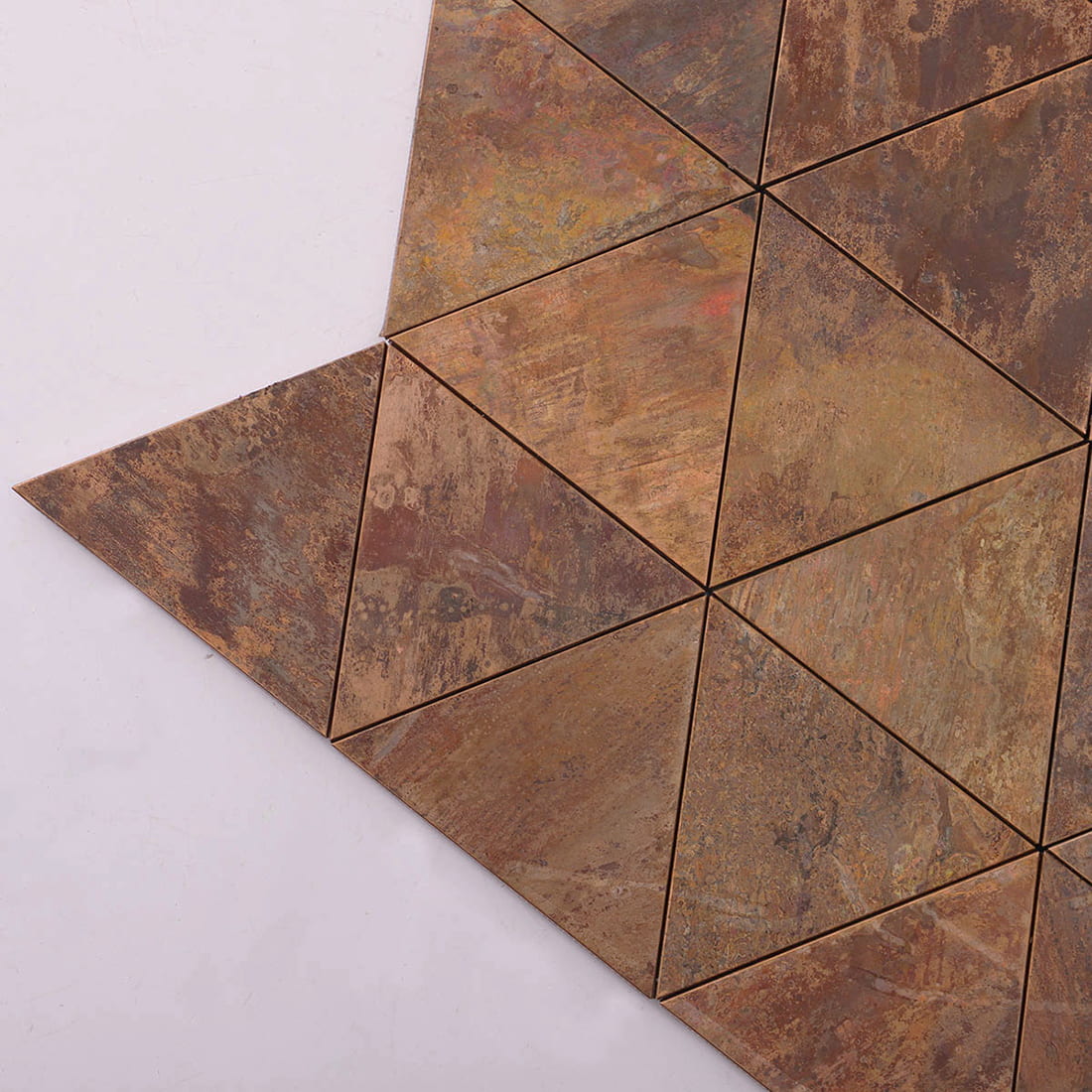 Close up showing the edge of a rustic copper triangle metal tile.