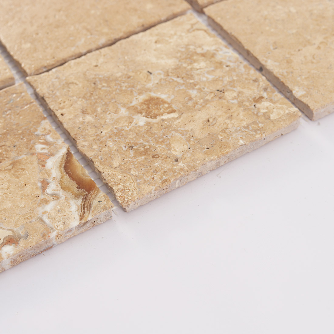 Side detail of beige limestone square tile showing thickness and rough edge