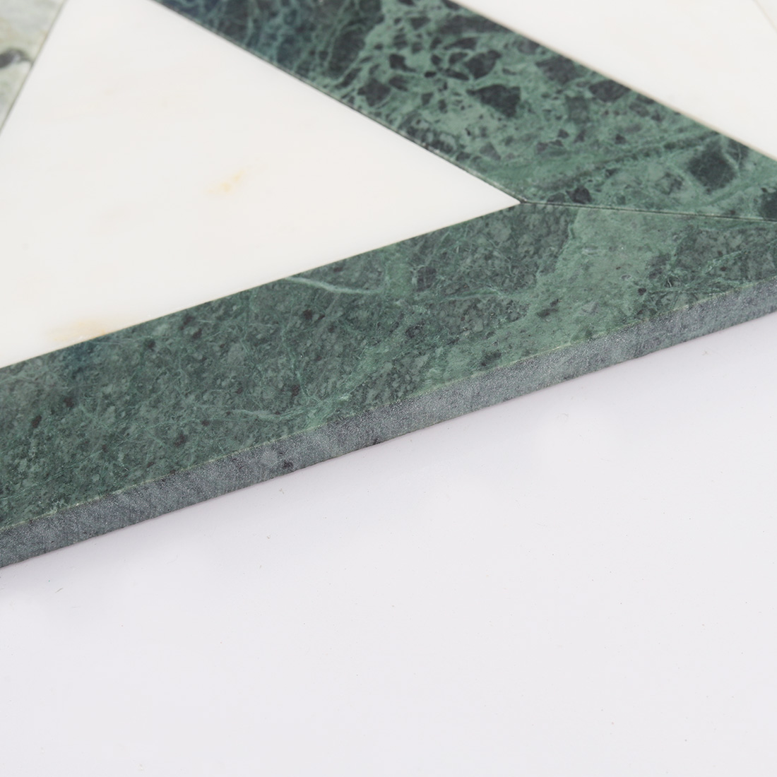 Side detail of green and white geometric marble tile showing stone thickness