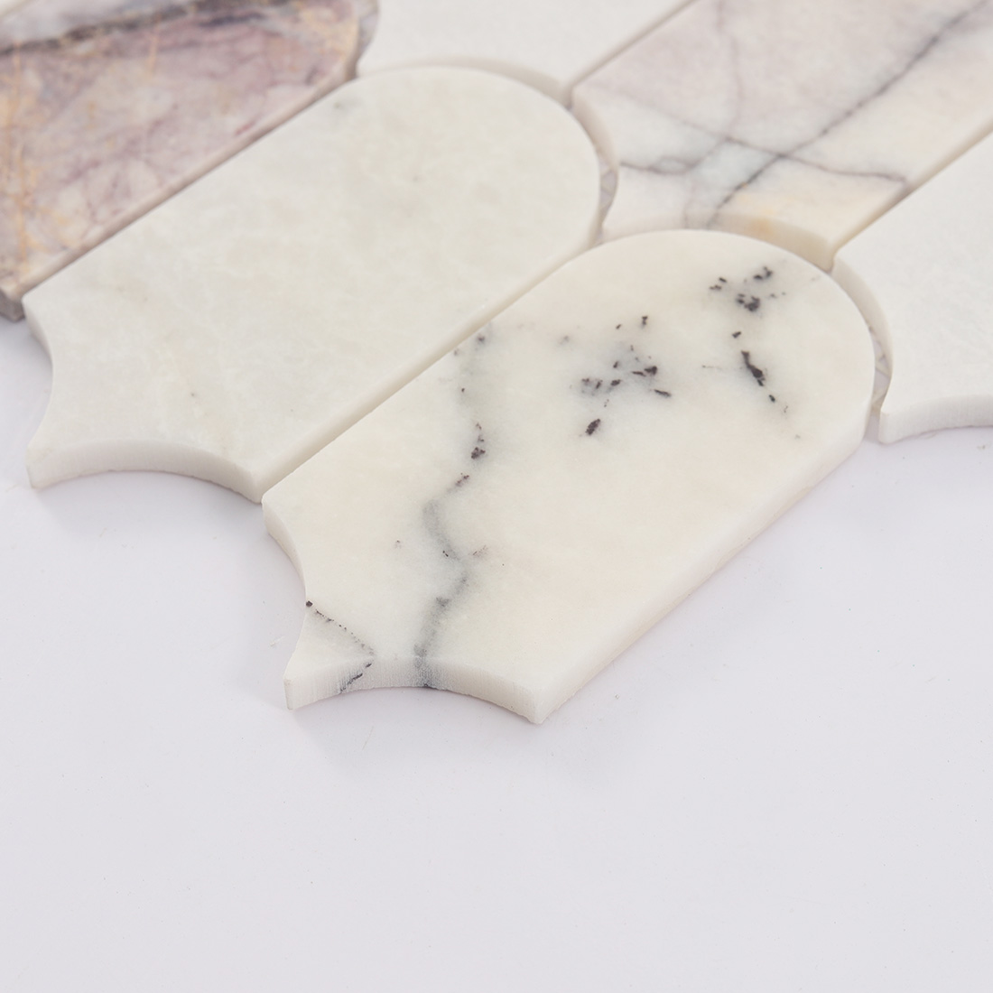 Side detail of white arched marble mosaic tile showing curved stone edge