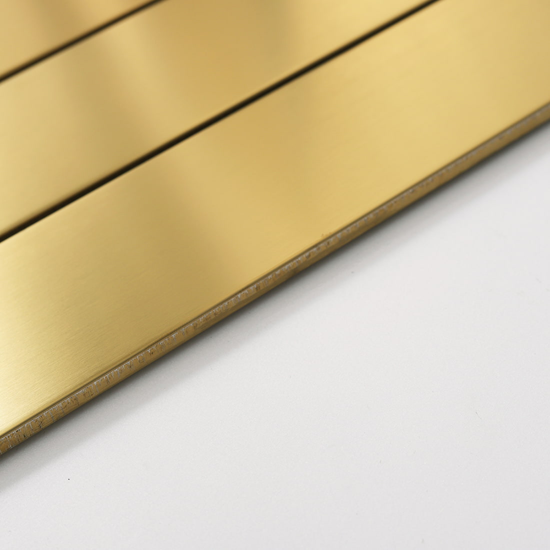 Side view showing the thickness and edge of gold linear tile.
