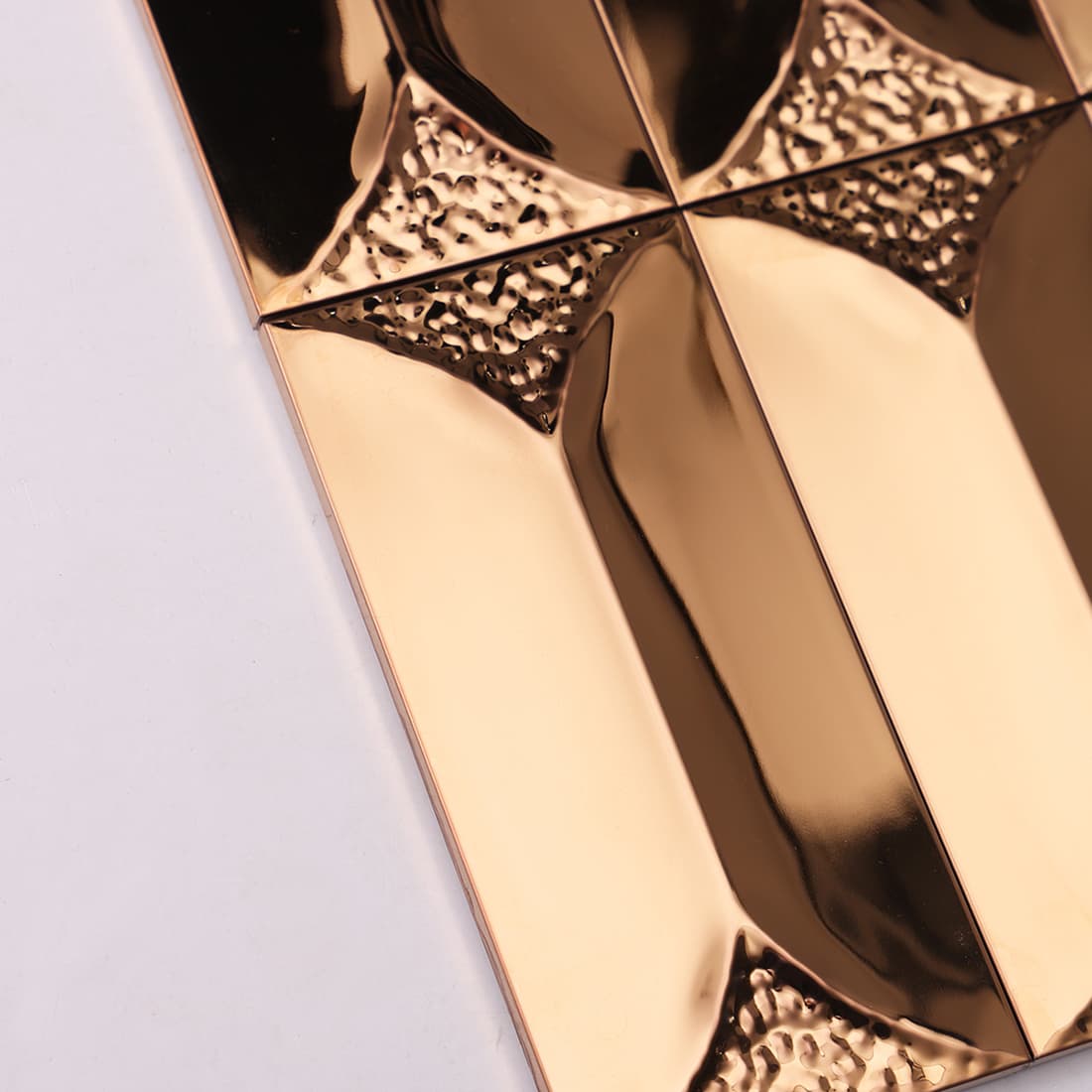 Side view showing the 3D depth and thickness of rose gold beveled metal tiles.