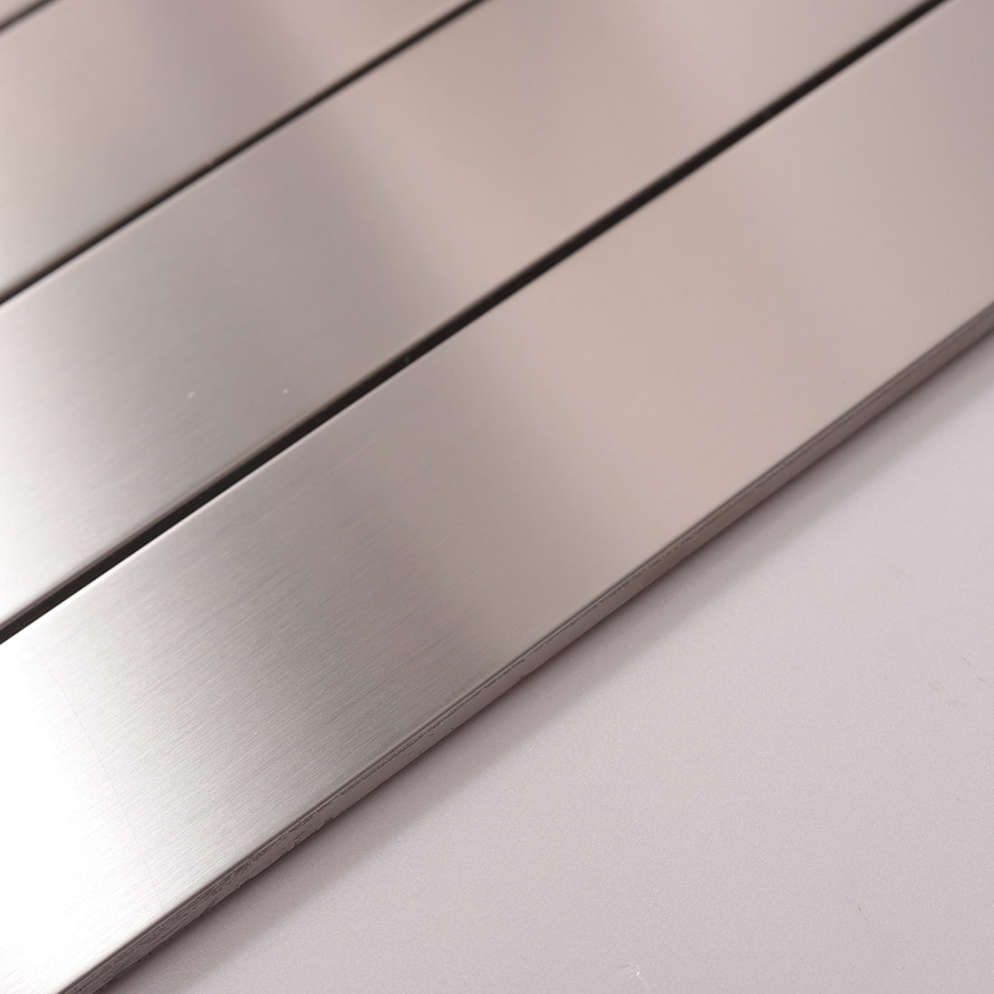 Side view showing the thickness and edge of silver brushed linear tile.