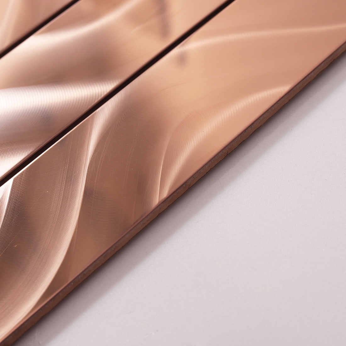 Side view showing the thickness and texture of rose gold flowy linear tile.