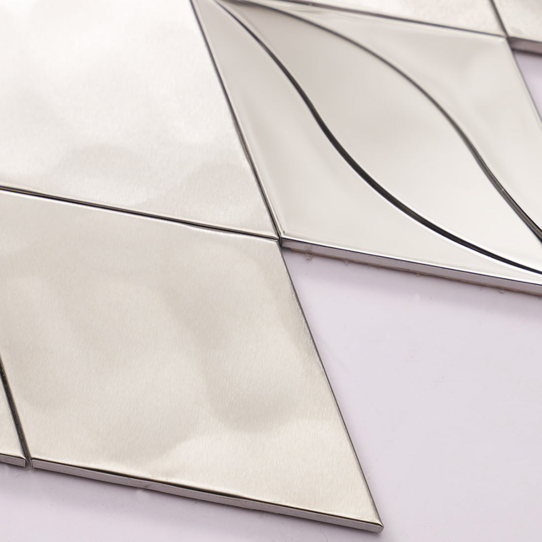 Detail of a silver mirror finish stainless steel tile with 3D leaf design.