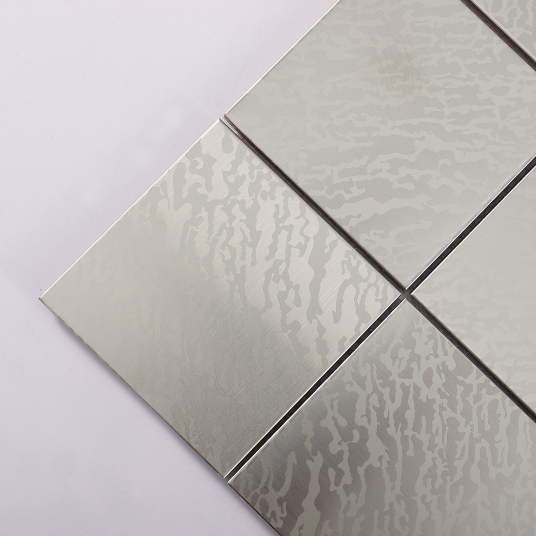 Close view of silver stainless steel square tile with etched wave texture