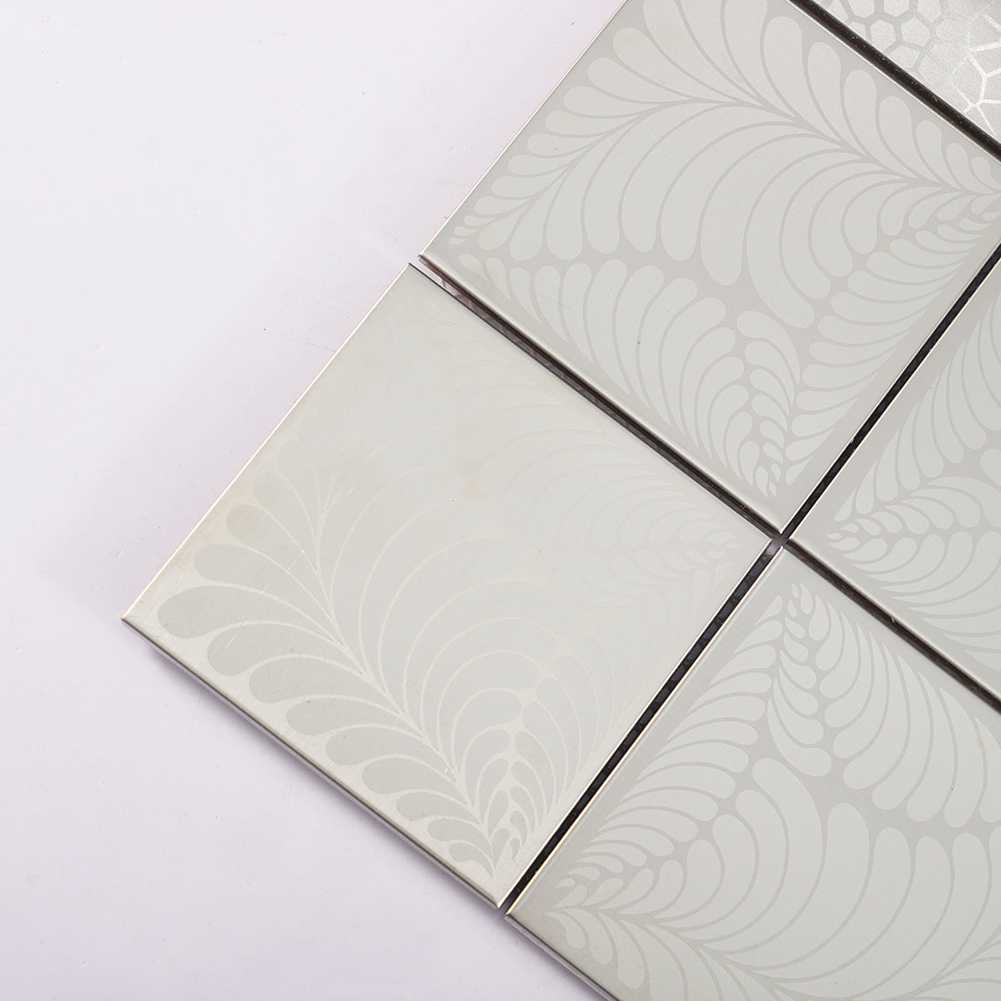 Close view of silver stainless steel square tile with floral engraved pattern