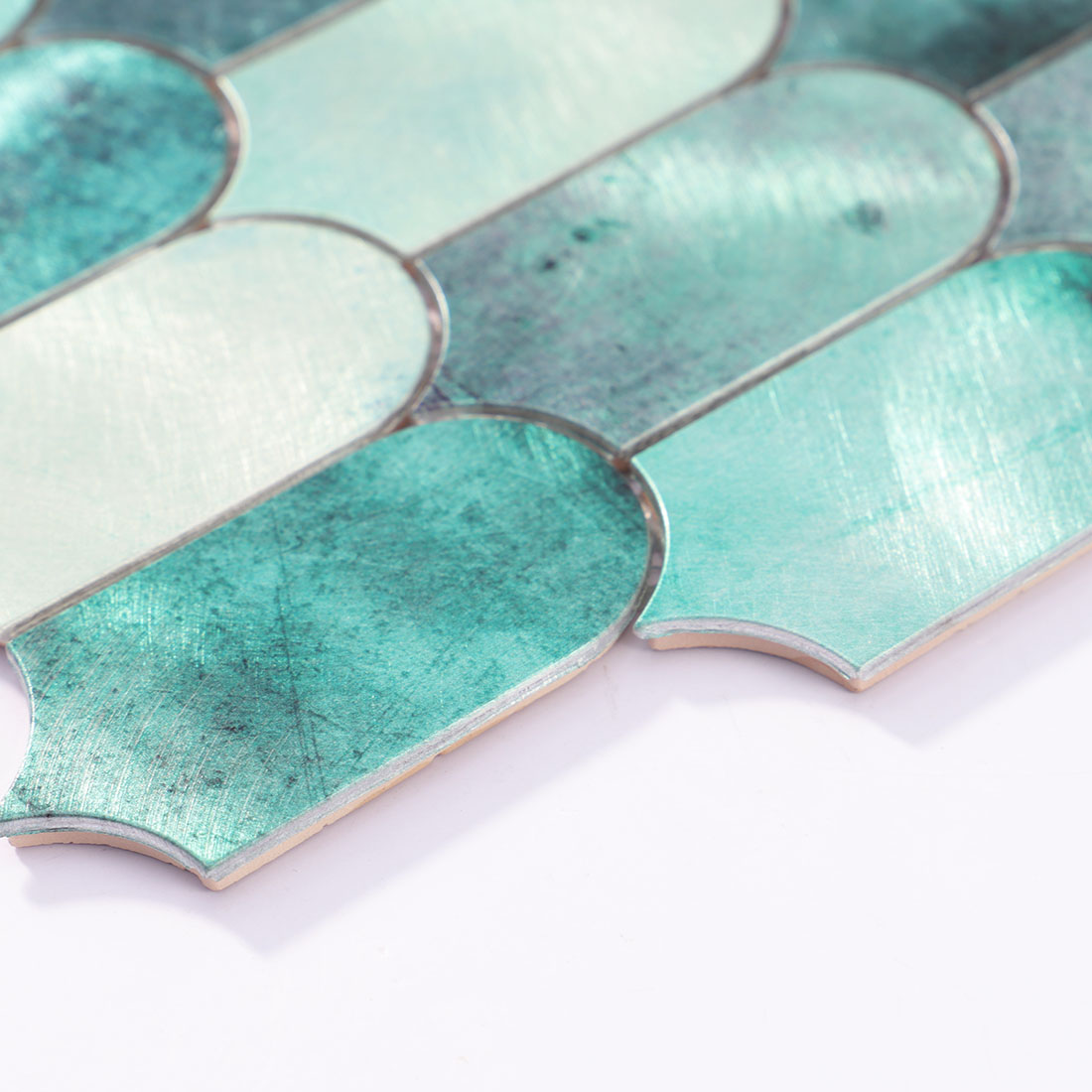 Angle shot of teal green arched aluminum mosaic tile showing edge