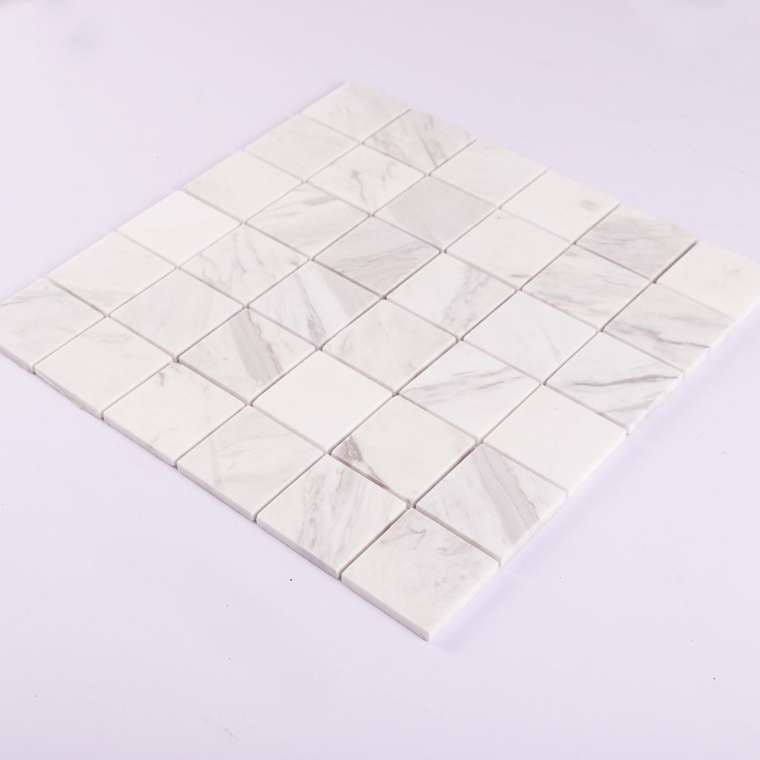 Angled view of Volakas white square marble mosaic tile sheet