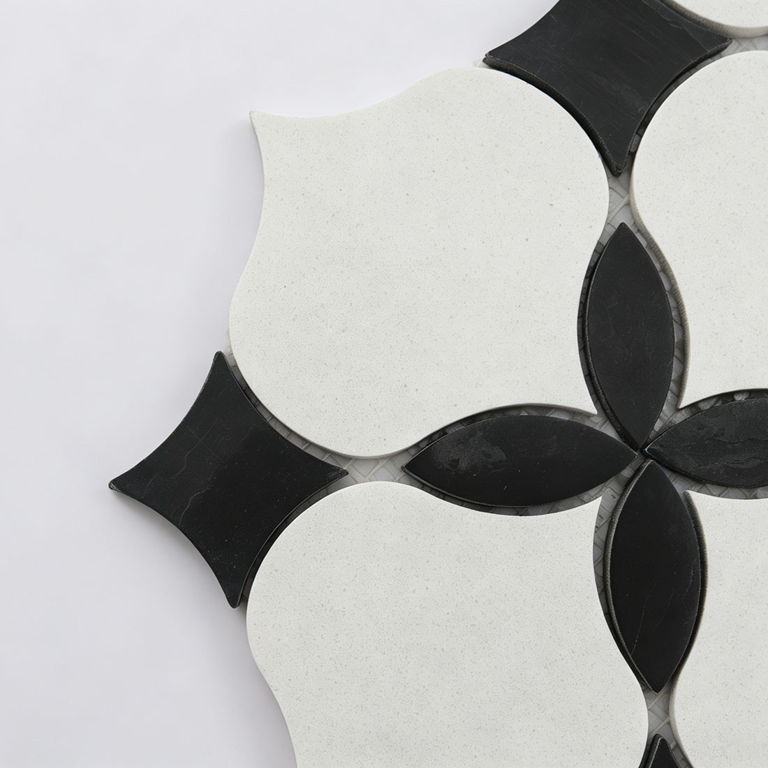 Close-up of white arabesque marble pieces with black petal and curved square accents