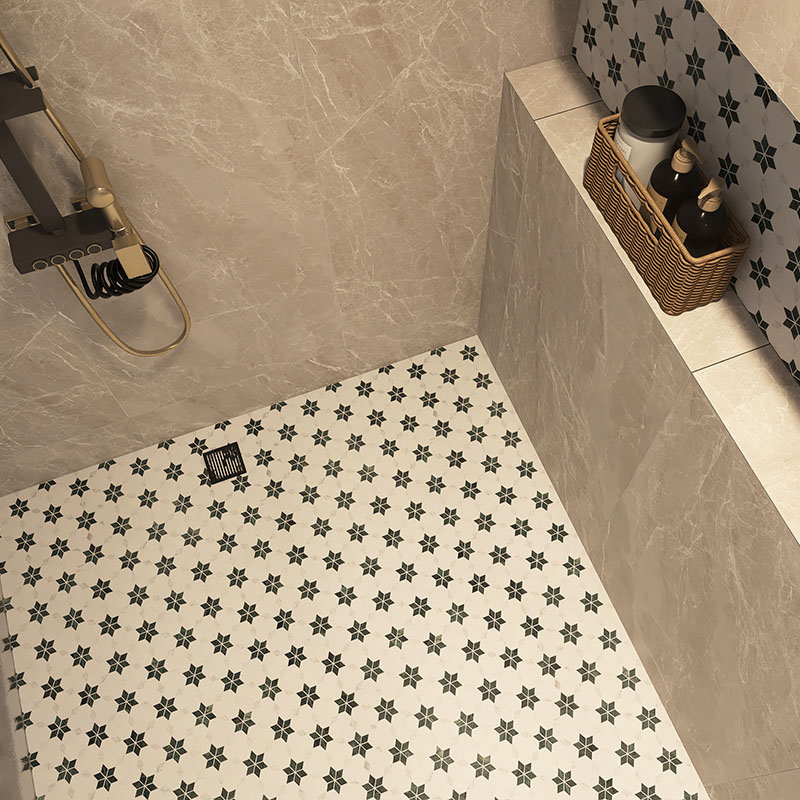 Wide view of a white floral mosaic shower floor in a beige tiled shower