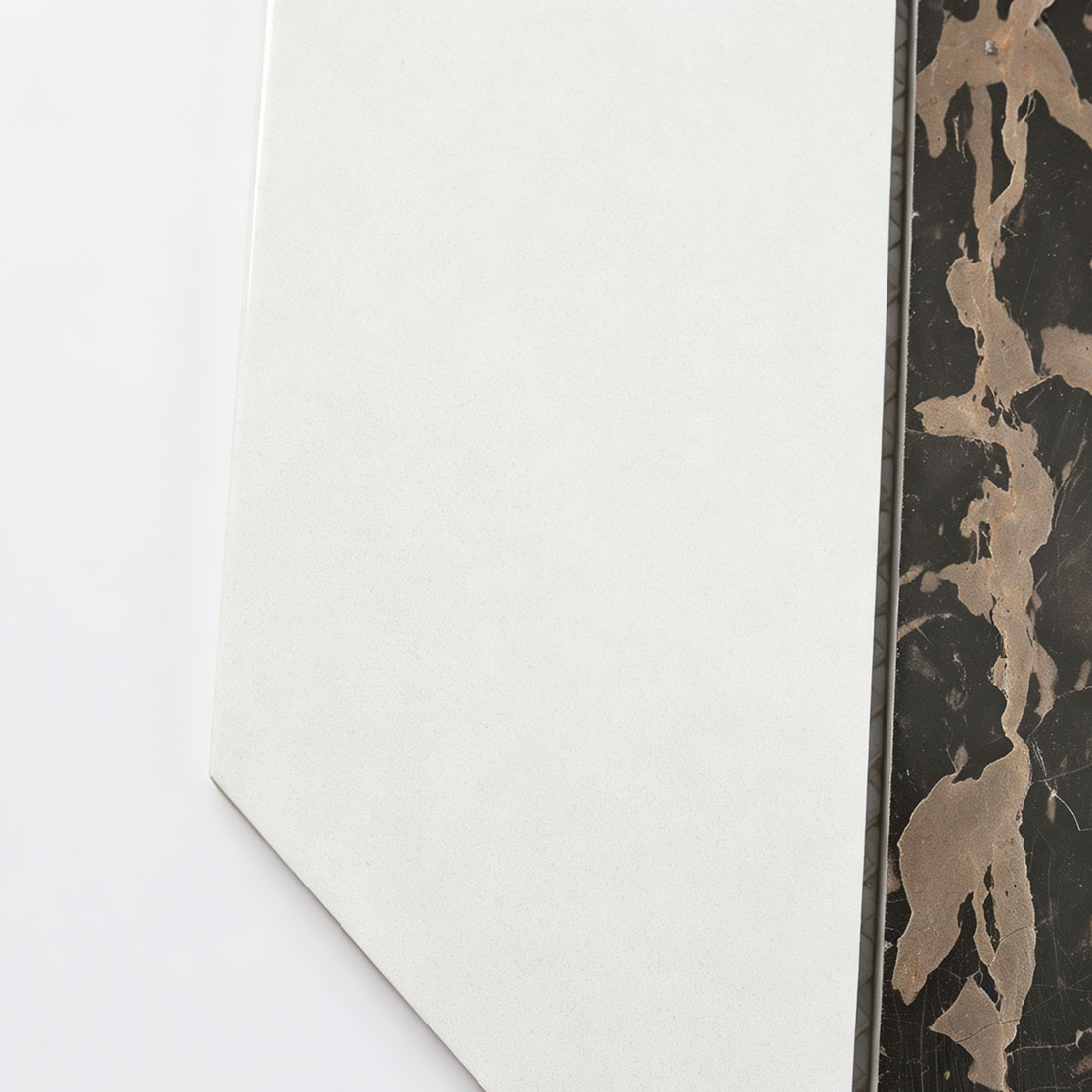 Close-up of white geometric marble mosaic tile beside brown veined marble