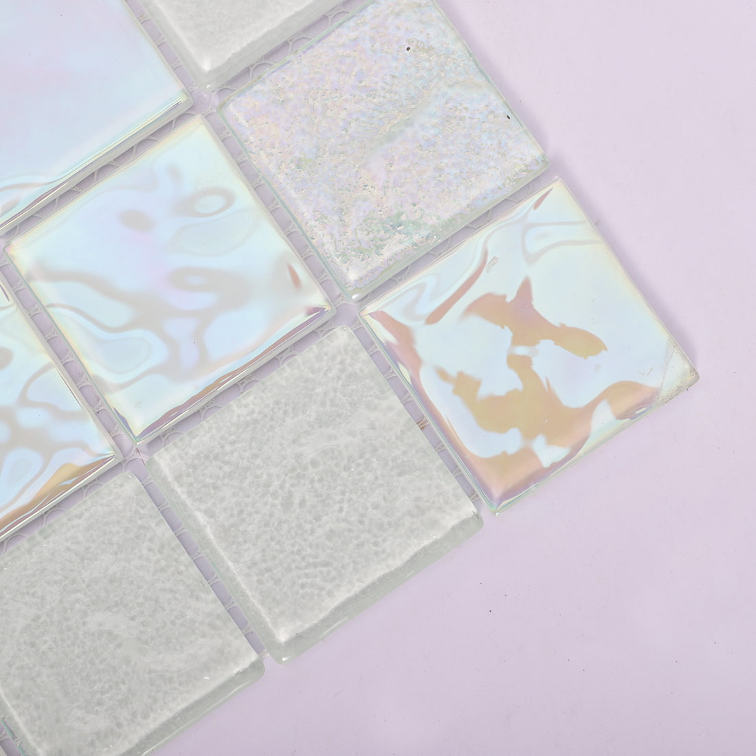 Corner detail of white iridescent square glass mosaic tile on pink background