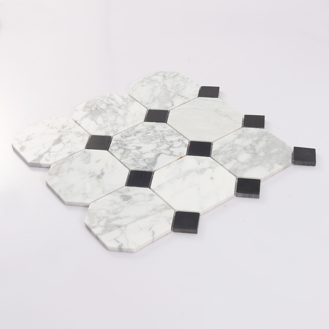 Angled detail of white marble octagon mosaic tile with raised black dot pieces