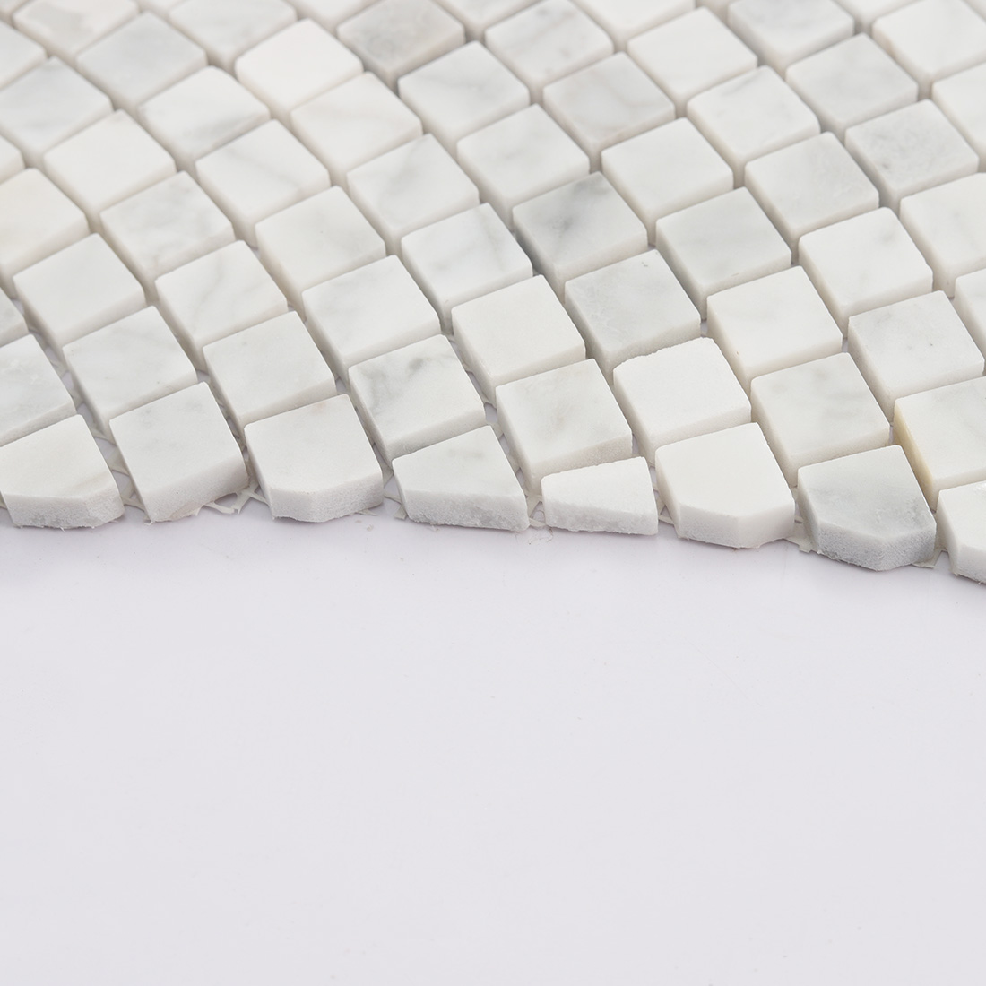 Edge detail of white marble square mosaic showing tile thickness