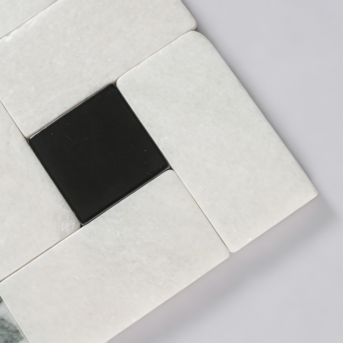 Close-up detail of black square accent on white marble mosaic