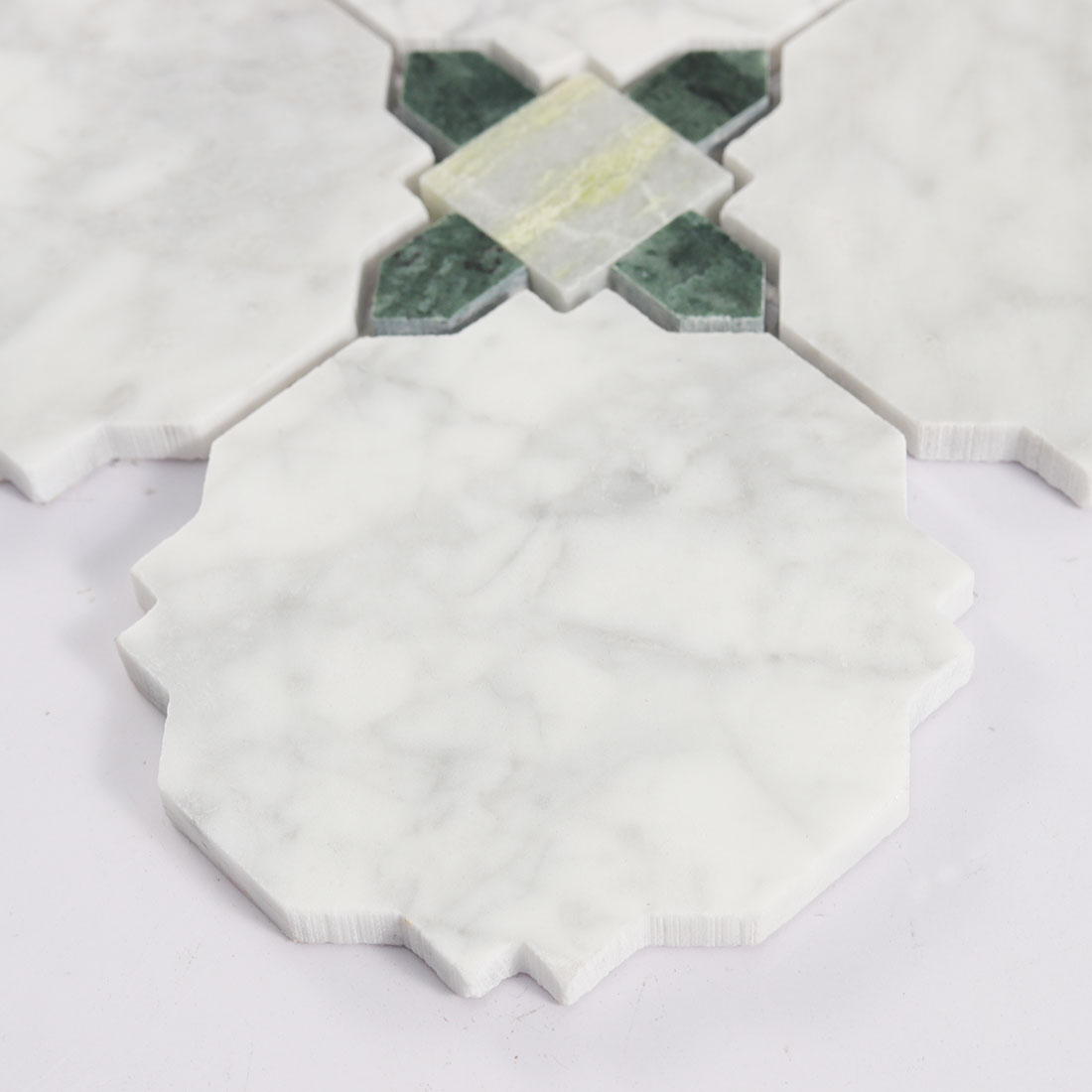 Close up of white octagon marble tile edge with green stone square accent