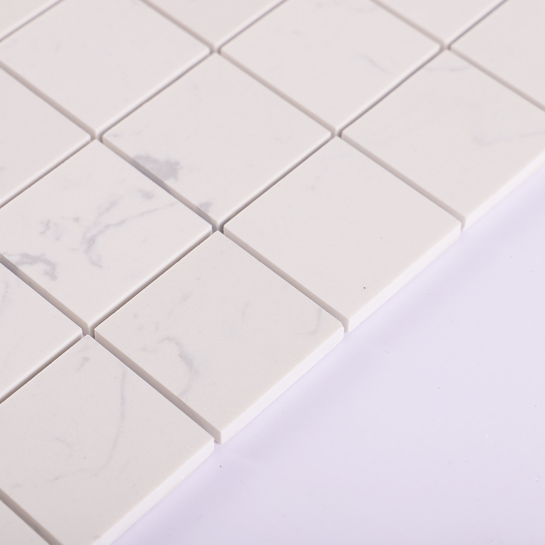 Edge detail of white square marble mosaic tile with light gray veining