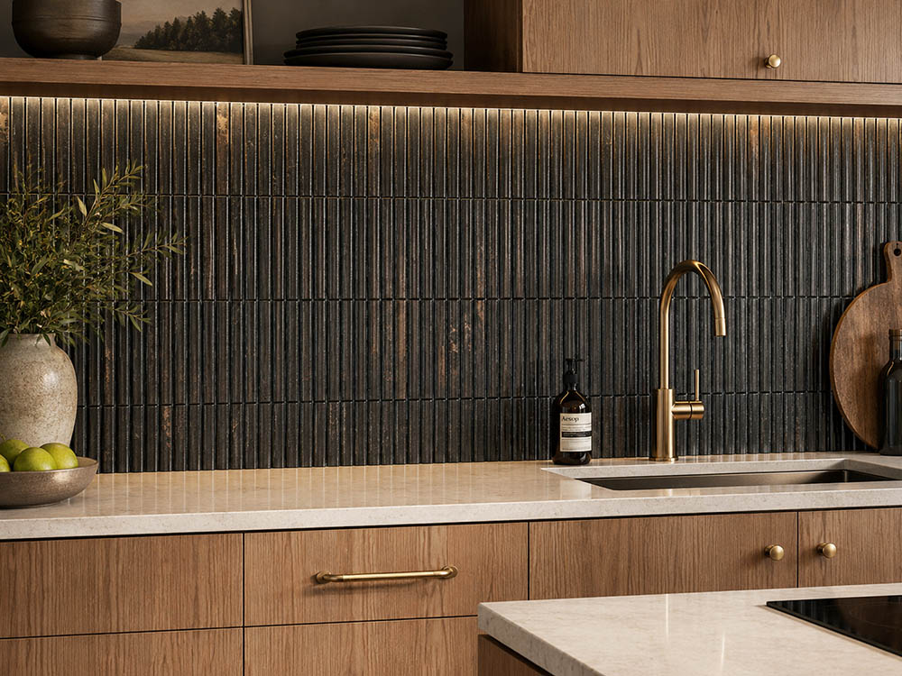 Wide kitchen view with black fluted tile backsplash and light wood cabinets