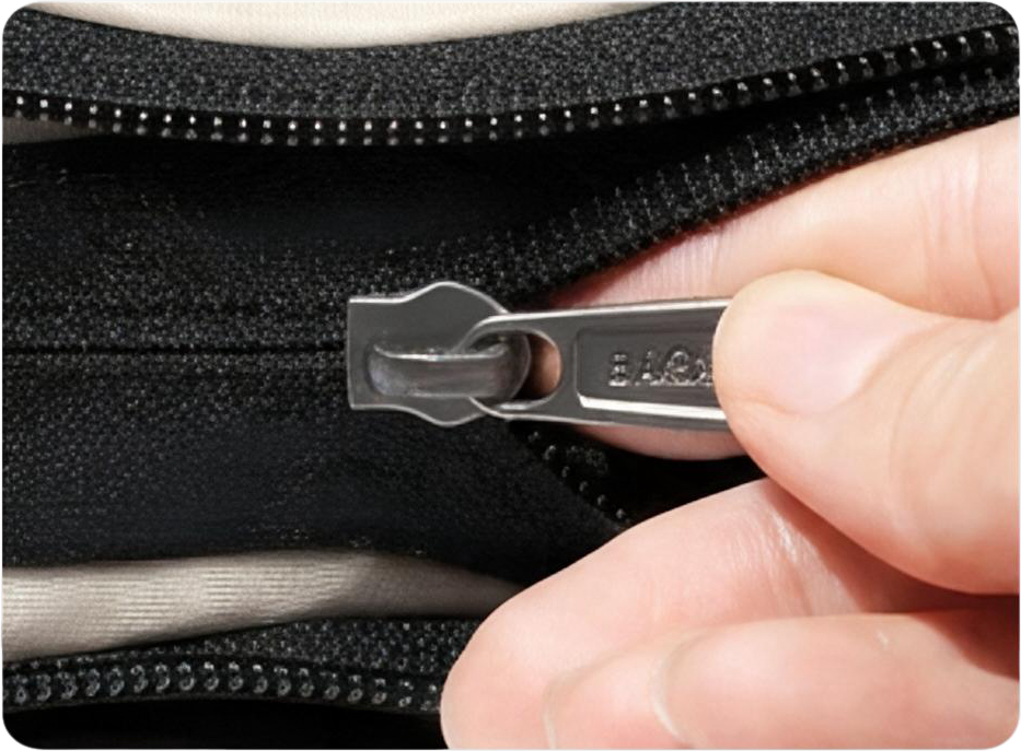 Close-up of a finger behind the metal zipper slider while compressing