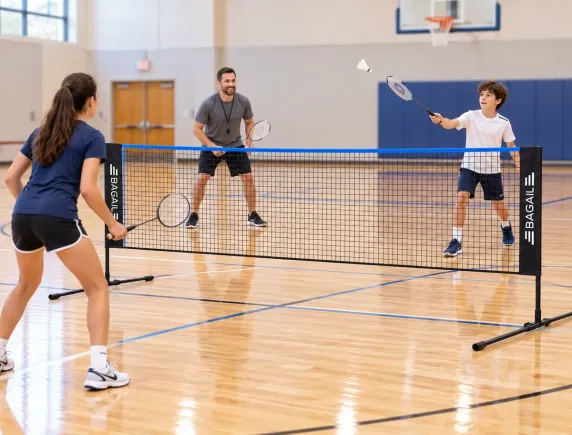 The freestanding net standing on an indoor gym floor beside the court line