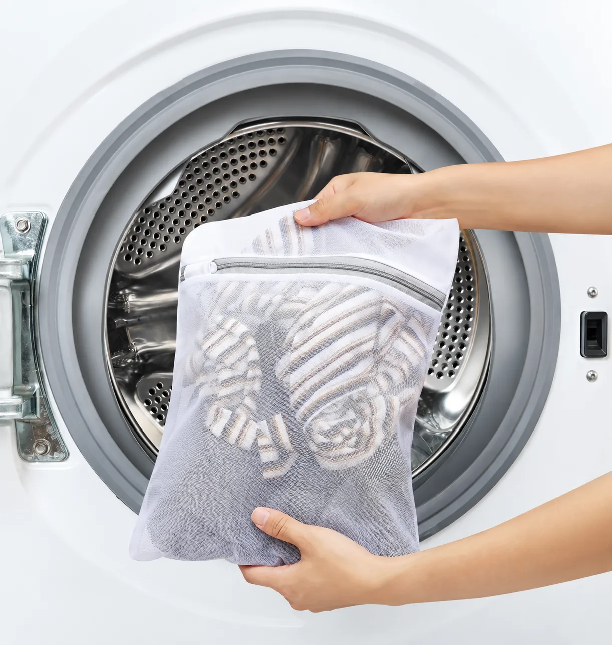 Hands placing a BAGAIL mesh laundry bag into a washing machine