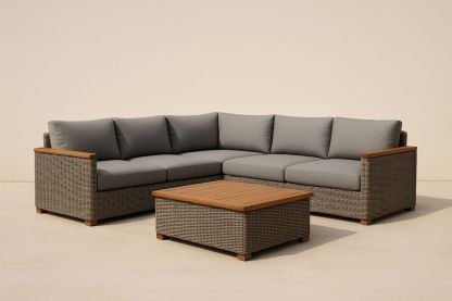 Divano angolare in rattan sintetico con cuscini grigi e tavolino in legno