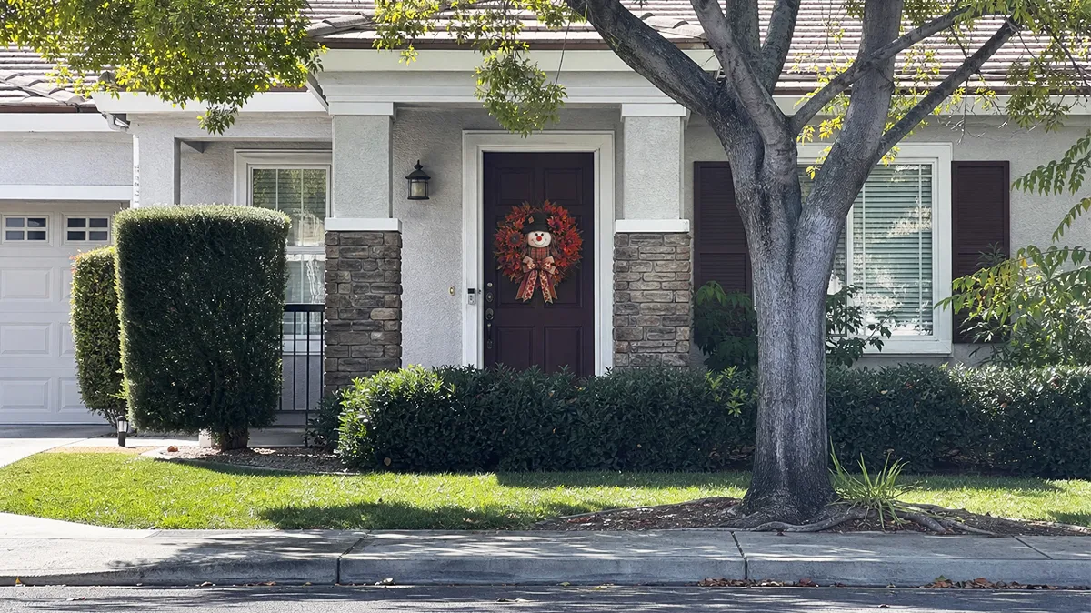 Scarecrow fall wreath displayed on a home front door from the street
