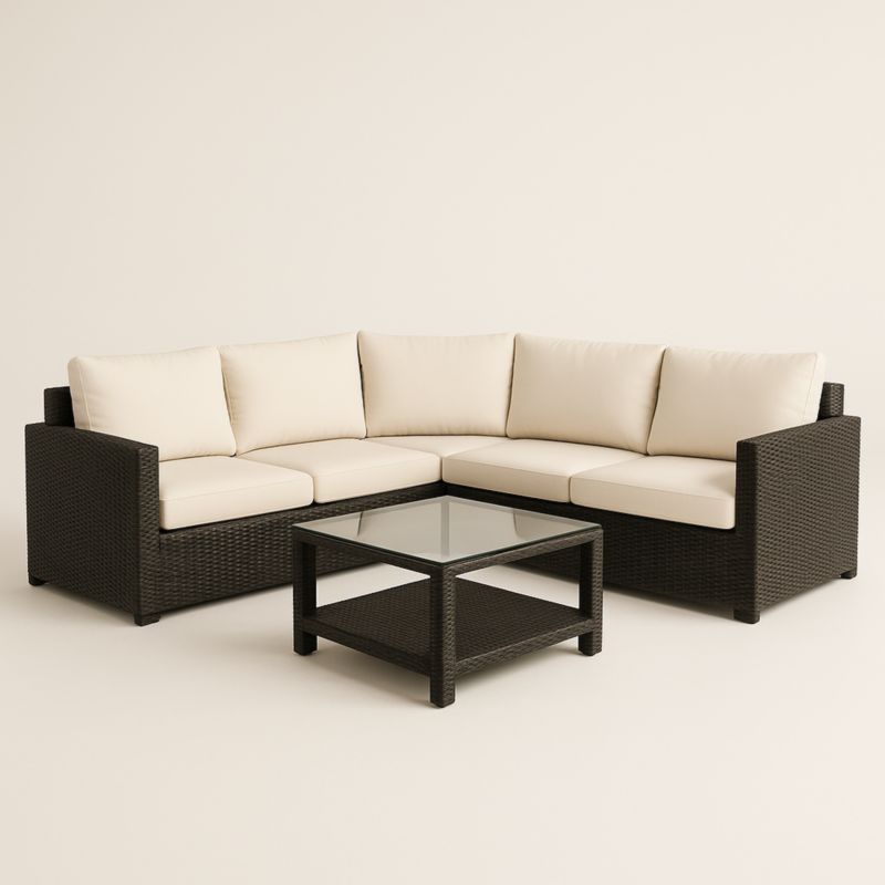 Divano angolare in rattan con cuscini bianchi e tavolino in vetro