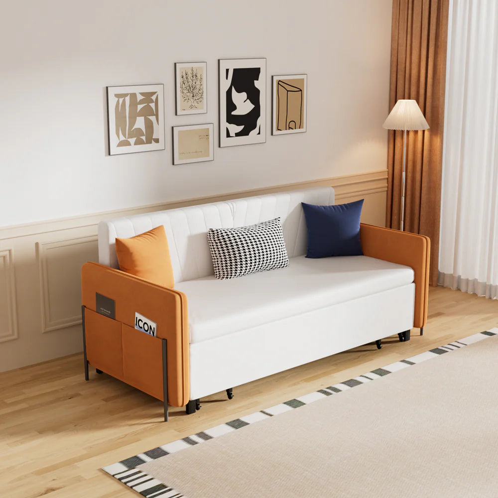 Modern compact sofa bed with white upholstered seat and back cushions, camel-brown side panels with built-in magazine pocket, styled in a bright minimalist living room with framed wall art.