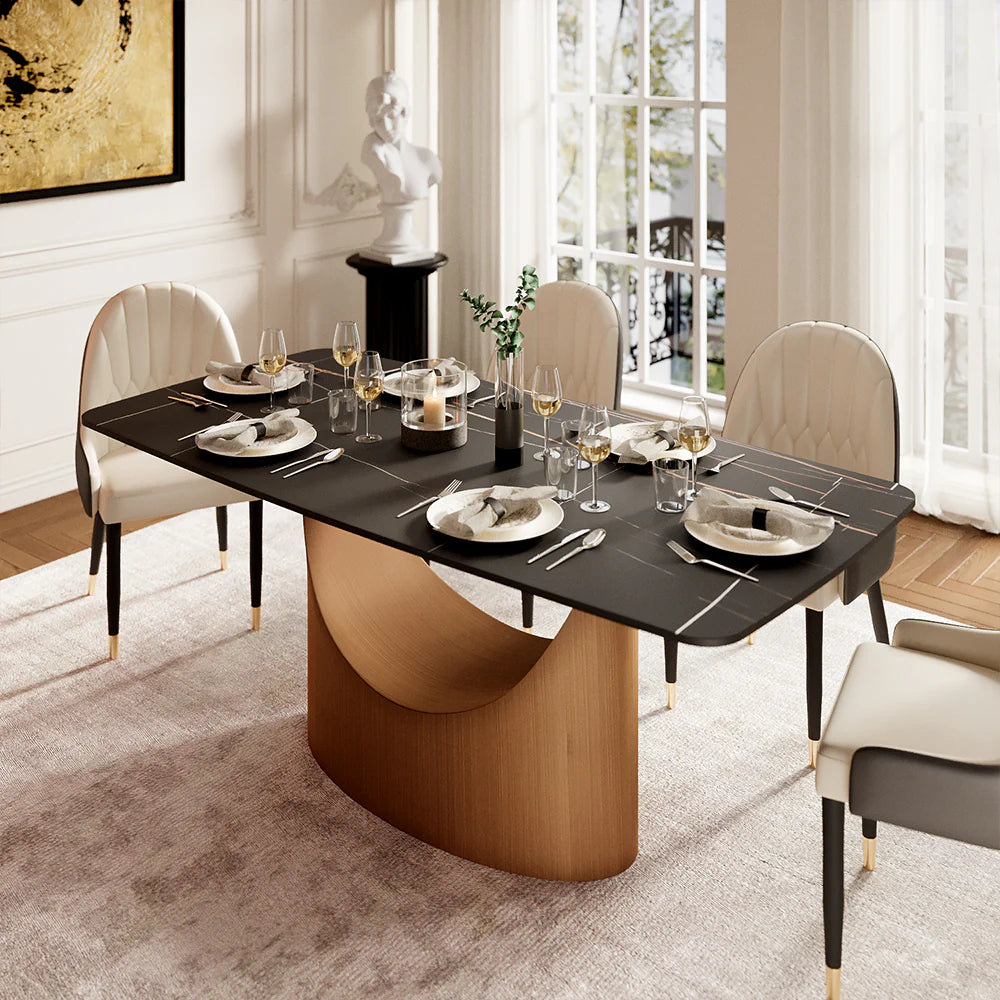 Matte black dining table with sculptural wood base, styled in an elegant dining room with upholstered chairs and warm lighting.