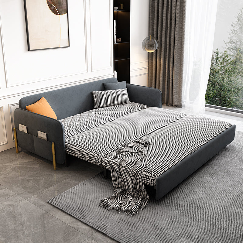 Gray velvet sleeper sofa with a blanket and pillows in a modern living room.