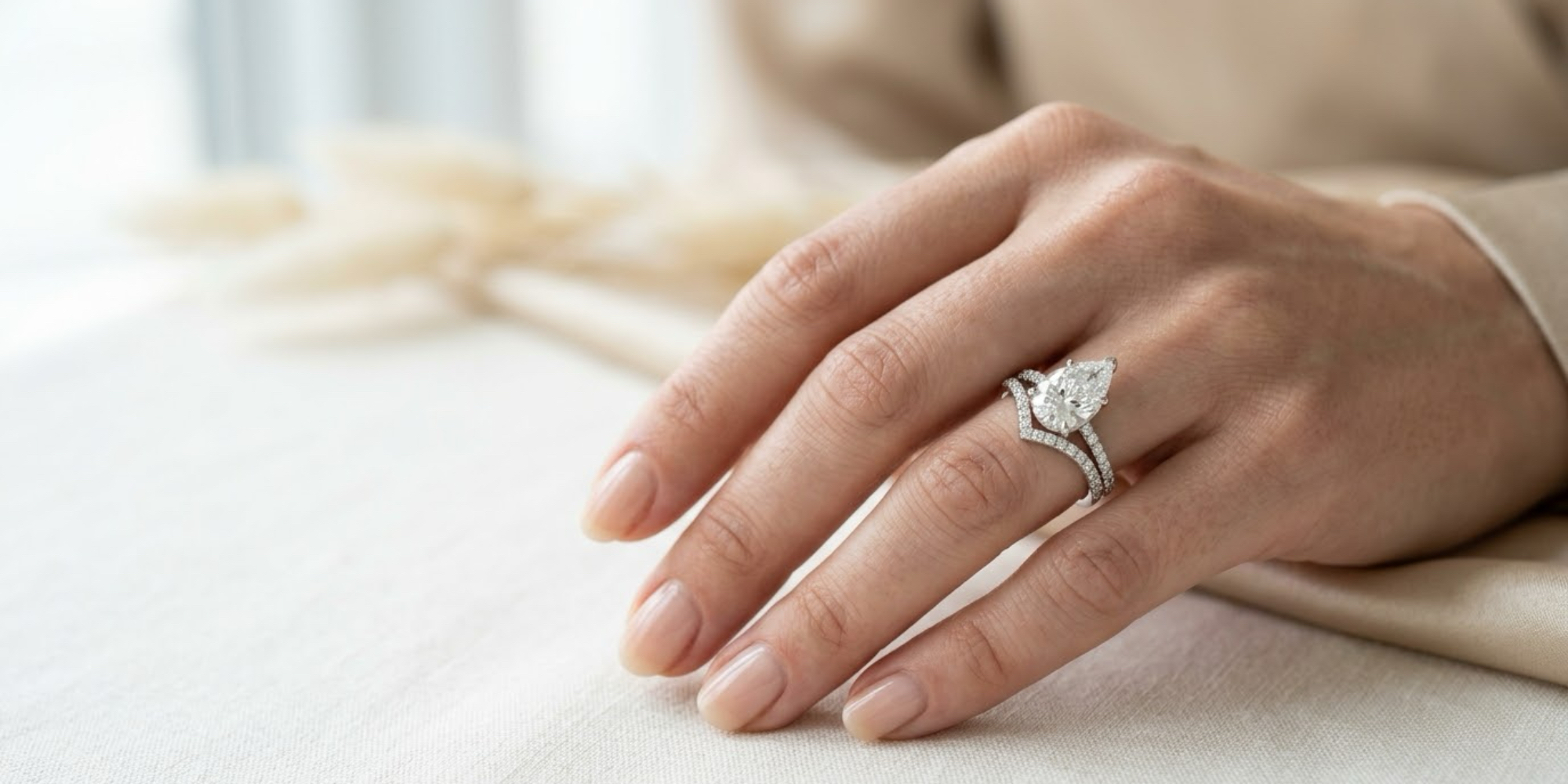 Pear-shaped diamond engagement ring paired with a contoured V-shaped pavé wedding band in yellow gold.