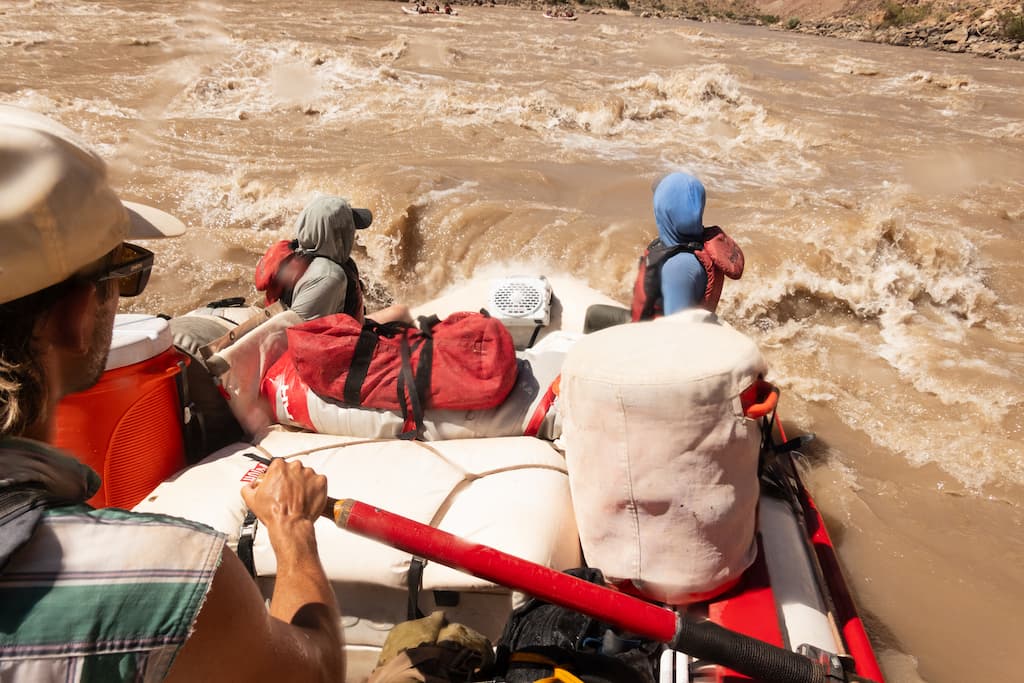 A group of people in a boat doing Rafting with a Turtlebox Original speaker attached to the boat