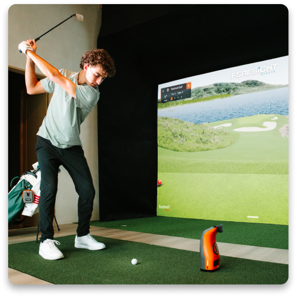 Person swinging a golf club in a simulated golf environment.