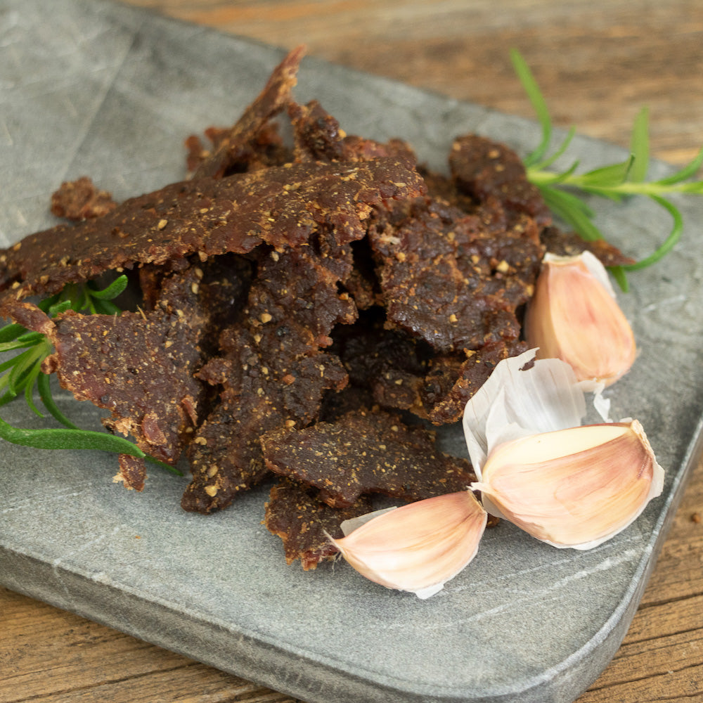 Tender cuts of Rosemary Garlicky Pilsner Boozy Jerky, infused with pilsner beer, fresh rosemary, and garlic, creating a rich, buttery steakhouse flavor.