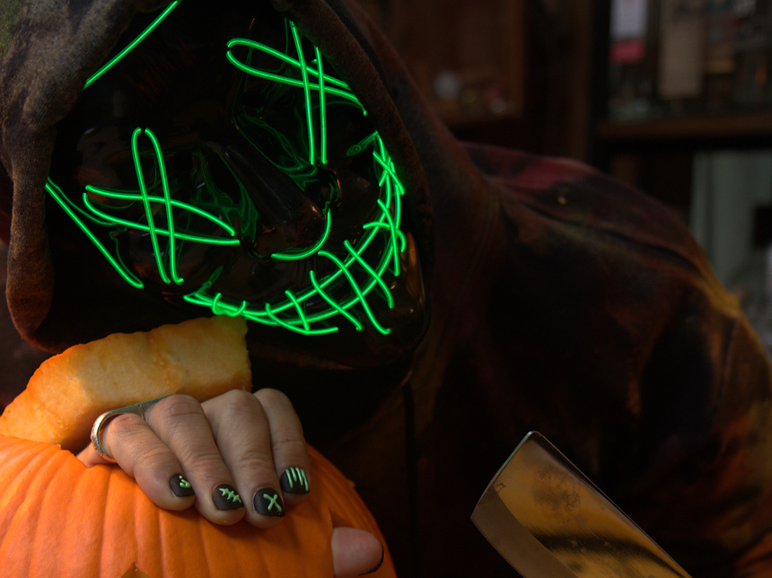 spooky halloween themed image of a man wearing the dark comedy reactive press on nail set, featuring raised 3D graphic designs that are UV reactive set on a solid black nail base