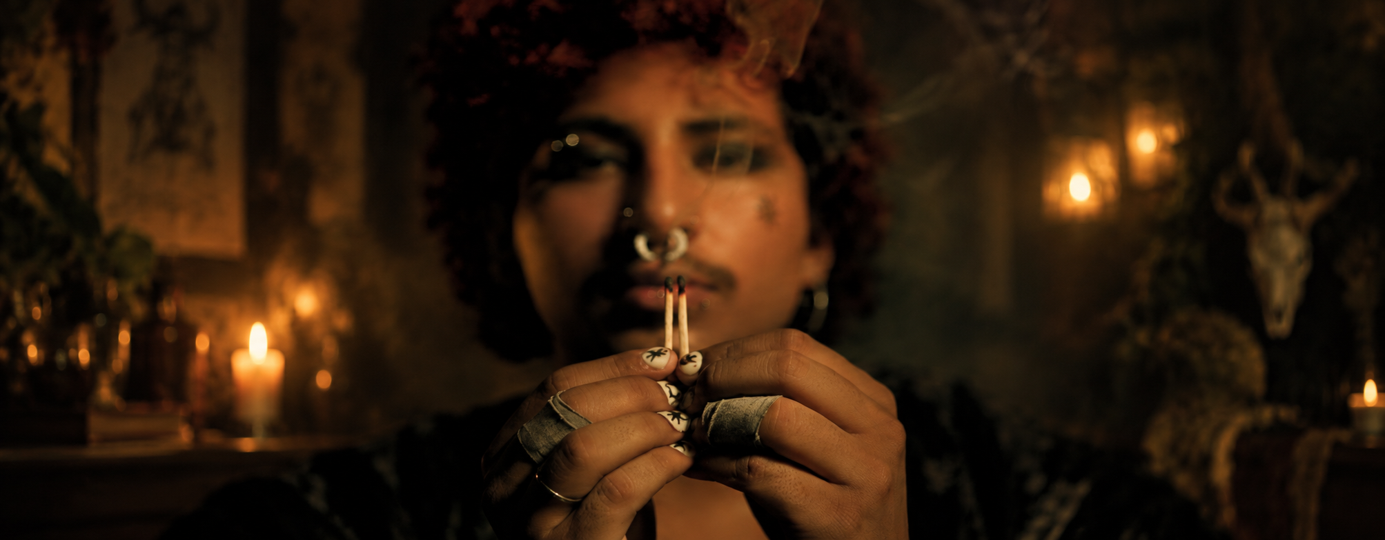 image of man in a moody, candlelit setting showing the sacred sigil press on nail set, which features a parchment colored nail base and black sigil graphics on each nail