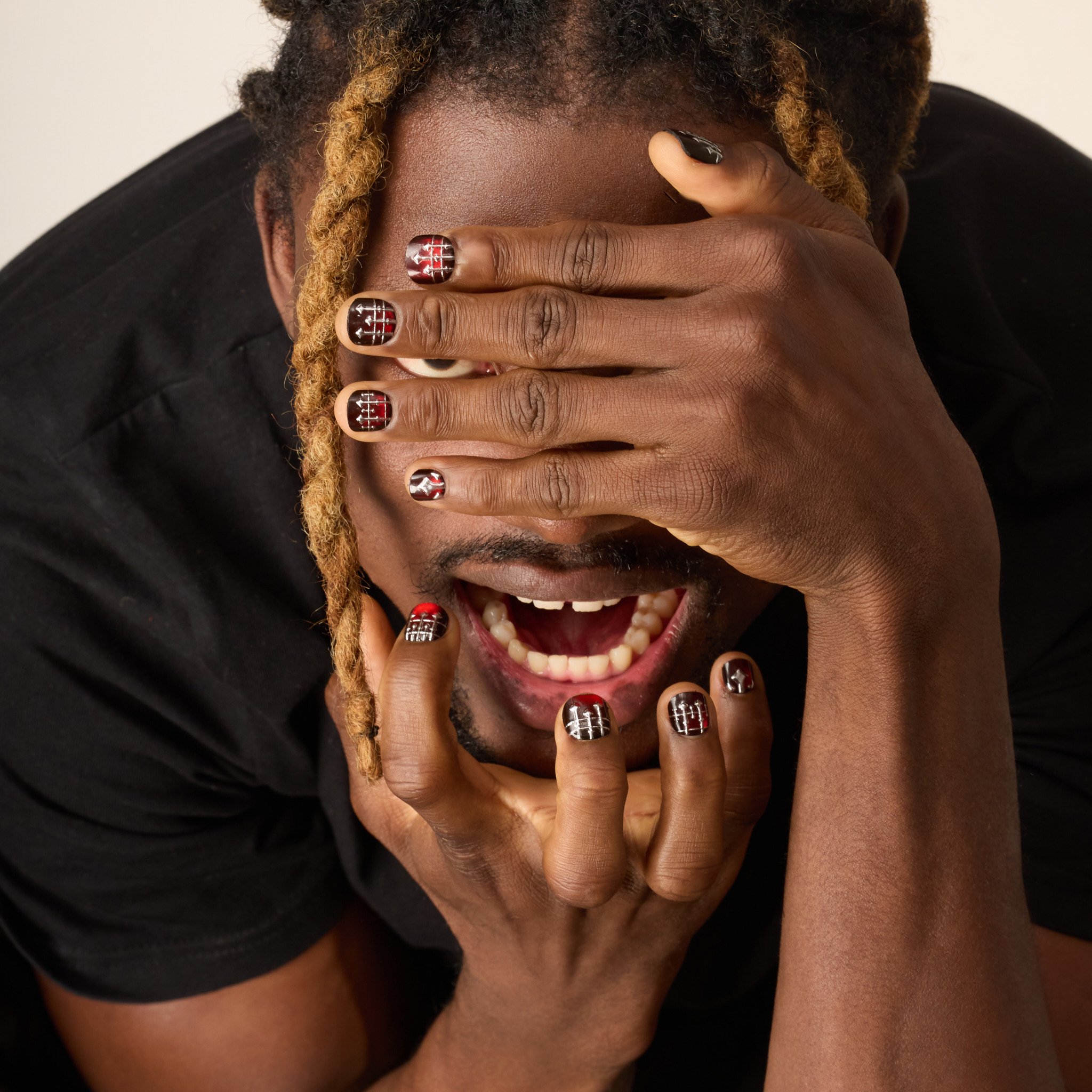image of man with hands in front of his face showing press on nails with deep red cateye base and a 3D ornate silver ironwork design