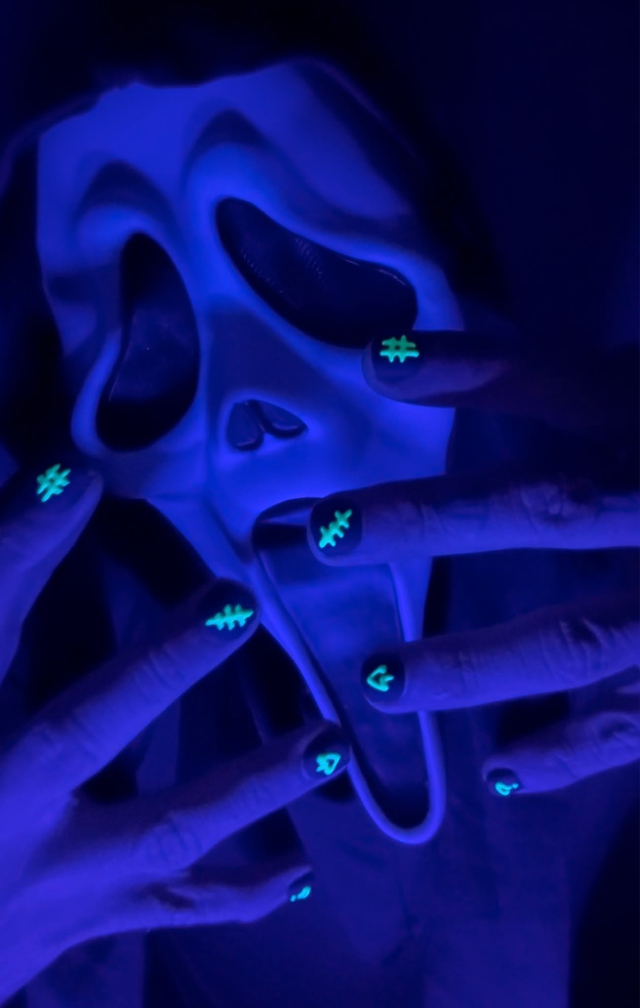 image of man in a halloween themed mask with hands in front of the mask featuring TALONS press on nails in style dark comedy reactive, featuring a black base with a glowing design