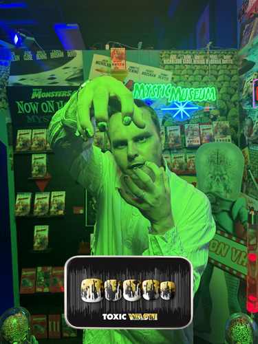 spooky Halloween themed image of a man wearing the Toxic Waste press on nail set, which features a dipped and splattered paint effect with a mixture of white, yellow, and black 