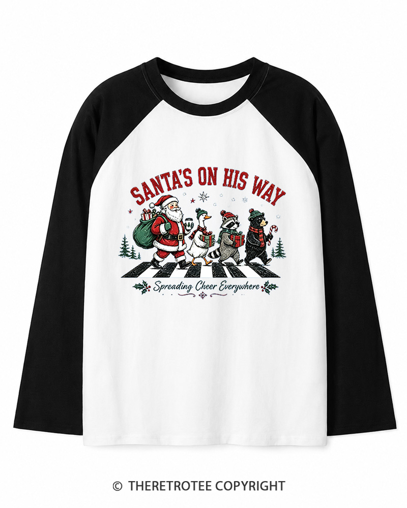 TheRetroTee Santa’s On His Way 1960s Christmas Long Sleeve Raglan T-Shirt