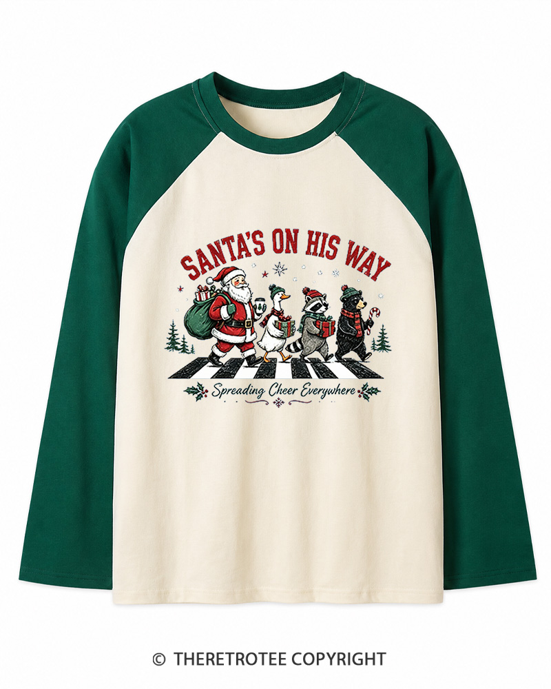 TheRetroTee Santa’s On His Way 1960s Christmas Long Sleeve Raglan T-Shirt