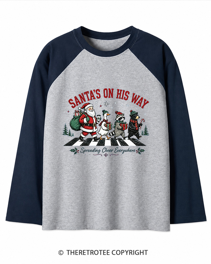 TheRetroTee Santa’s On His Way 1960s Christmas Long Sleeve Raglan T-Shirt