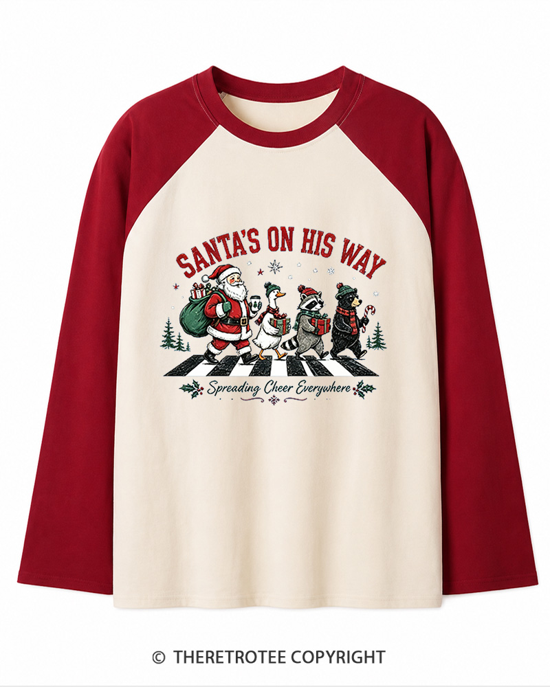 TheRetroTee Santa’s On His Way 1960s Christmas Long Sleeve Raglan T-Shirt