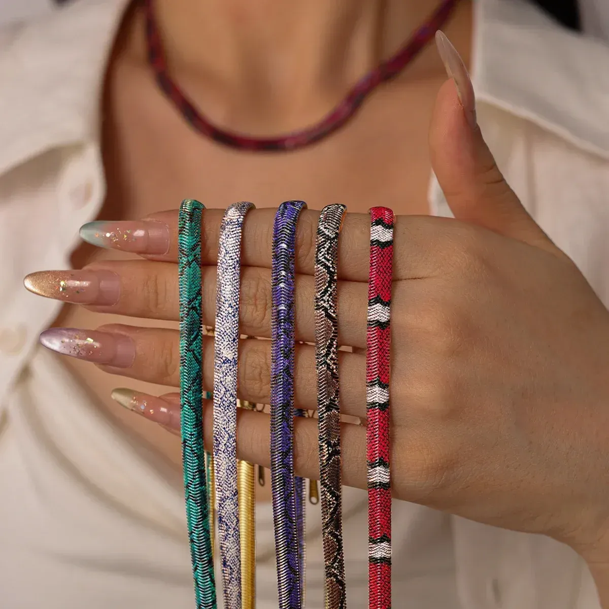 Hand holding the necklace in five different colourways