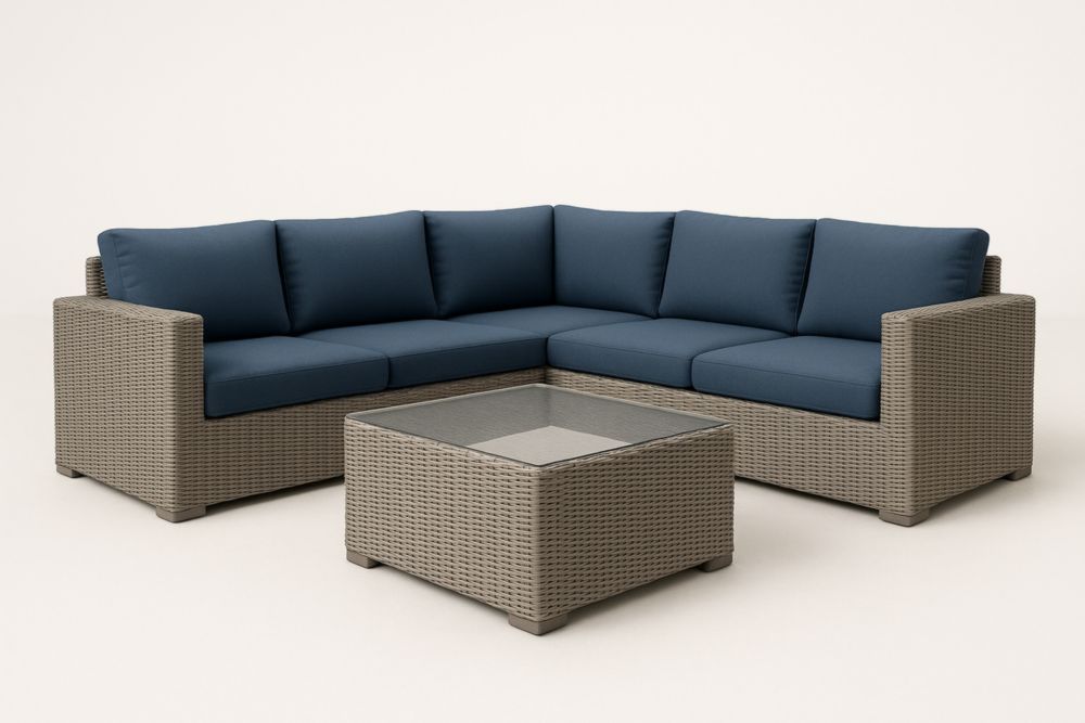 Set divano angolare in rattan con cuscini blu e tavolo in vetro