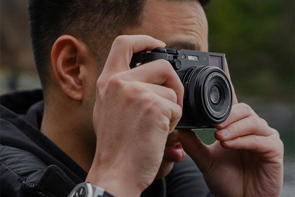 A man captures a handheld image in dim lighting.