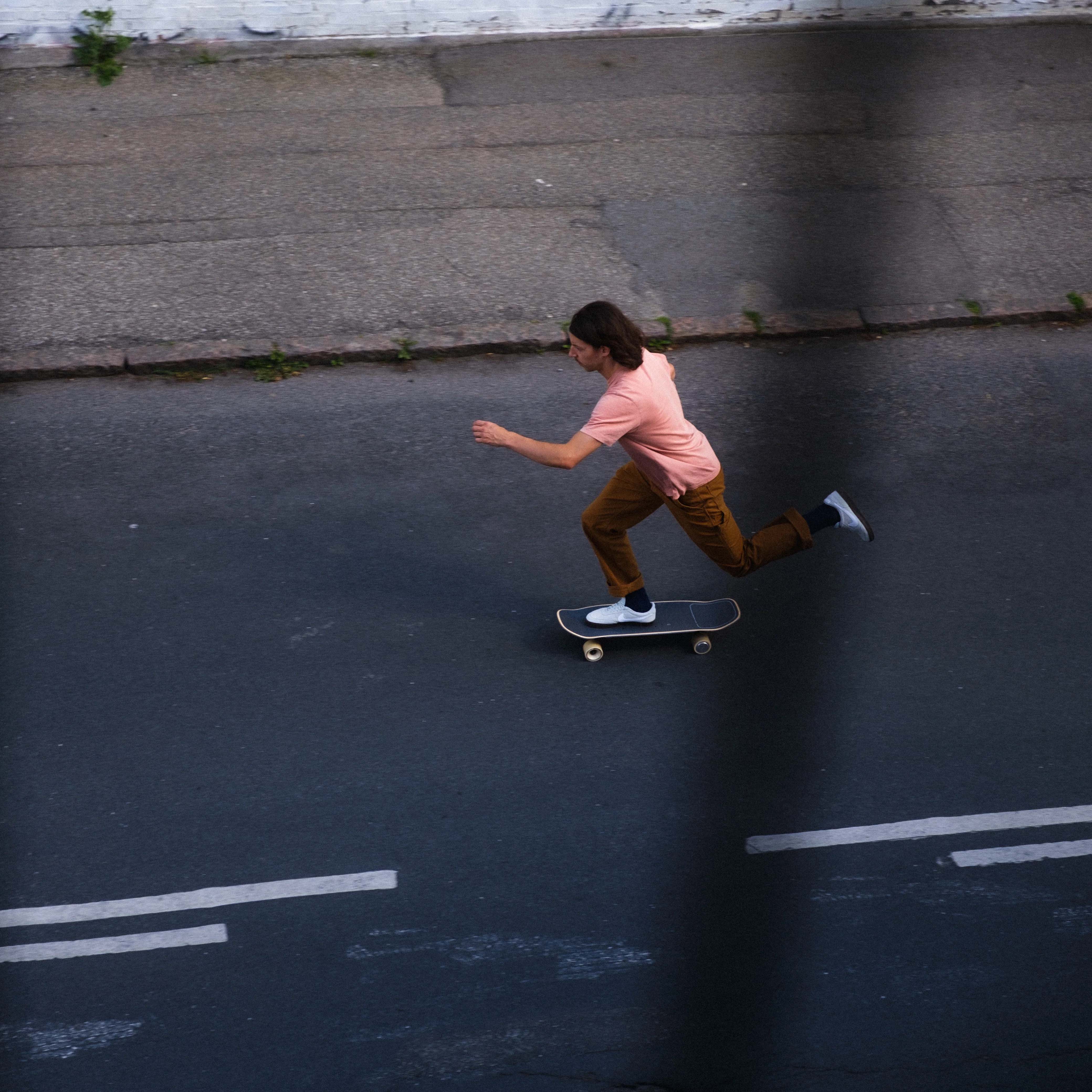 Rider pushing off on a compact electric skateboard along an urban street