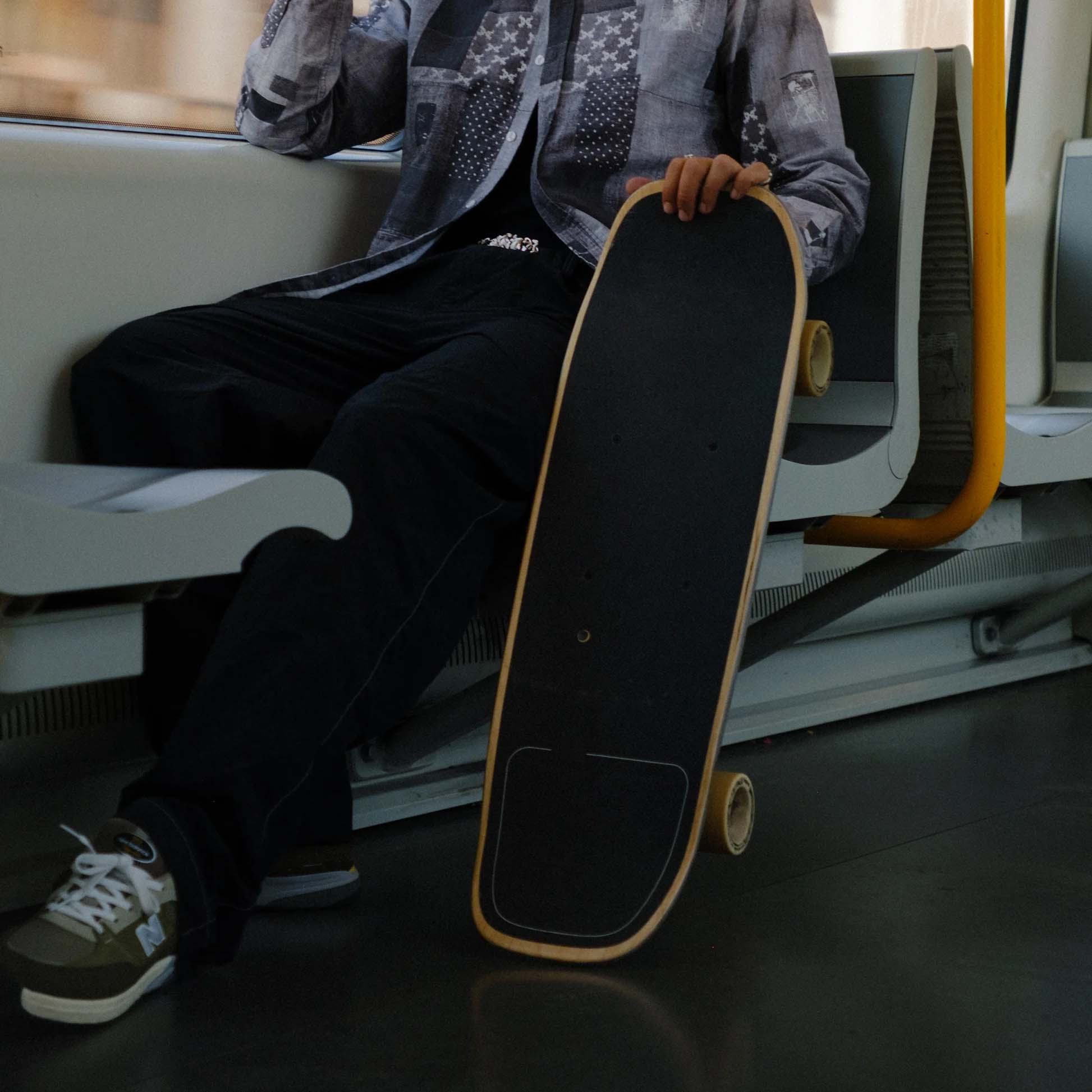 Compact skateboard held beside a passenger seat on public transportation